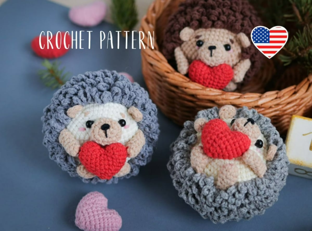  Two small crochet stuffed hedgehogs surrounded by gray spikes holding a small red heart next to a brown hedgehog with a red heart too.